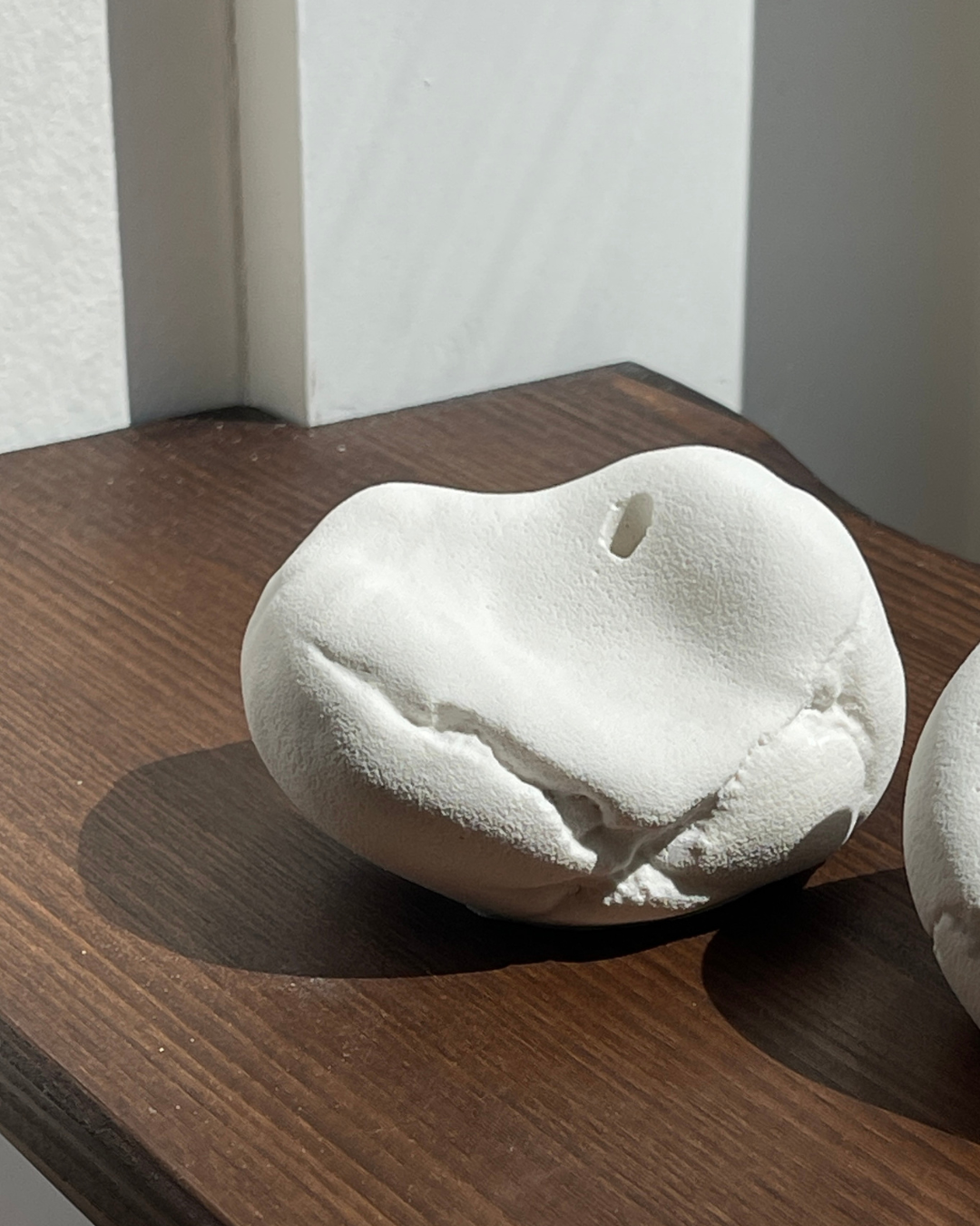 minimalist interior, white roses, ceramic vases, handmade decor, pebble vases, sculptural objects, wooden shelf, window light, sunlight shadows, neutral tones, aesthetic decor, soft natural light, floral arrangement, modern home, calm atmosphere, windowsill styling, organic shapes, artisanal pottery, natural materials, simple living, serene space, cozy corner, contemporary design, clean aesthetic, still life, home styling